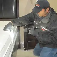 Bed bug inspection technician checking a mattress and bed frame for signs of infestation in Rochester, NY