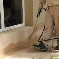 General pest control technician spraying exterior perimeter around a home in Rochester, NY