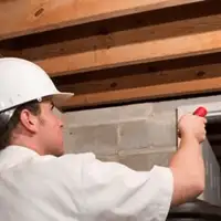 Termite inspection technician checking a basement wall and framing for termite activity in Rochester, NY